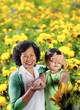 Photo: An old lady covering her granddaughter's eyes letting her touch the flowers in the park. An old lady covering her granddaughter's eyes letting her touch the flowers in the park.