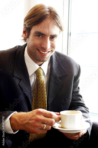 Photo: Man in business suit holding a cup of coffee. Man in business suit holding a cup of coffee.