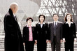 A bald man watching a group of business people standing in a row.