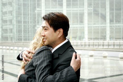 Photo: A man and a woman in business suits hugging. A man and a woman in business suits hugging.