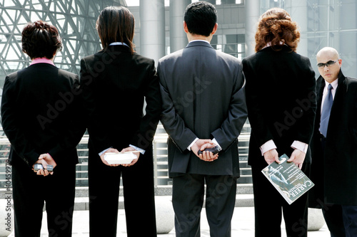 Photo: A baldman watching a group of business people standing in a row. A baldman watching a group of business people standing in a row.
