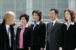 A bald man watching his employees standing at attention. 