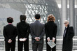 Back shot of business man and women standing in a row hiding their stuff. 