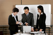 Manager showing some informations on his laptop to his assistants. 