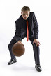 Man in business suit dribbling a basketball. 