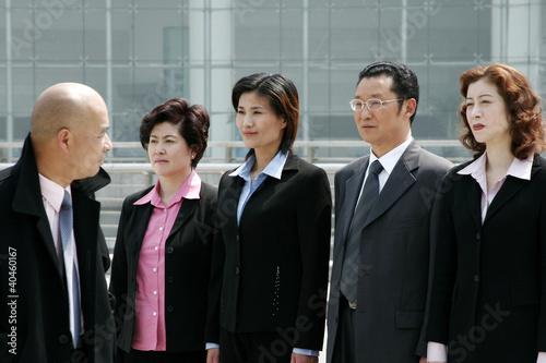 Photo: A bald man watching his employees standing at attention. A bald man watching his employees standing at attention.