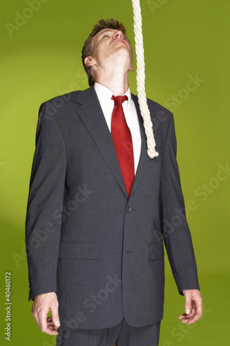 Foto: Man in business suit looking at a rope hanging from the top. Man in business suit looking at a rope hanging from the top.