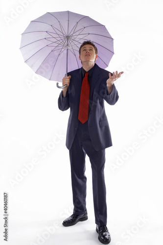 Foto: Man in business suit holding an umbrella while checking the weather. Man in business suit holding an umbrella while checking the weather.