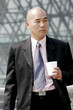 Photo: Bald man in business suit holding a cup. Bald man in business suit holding a cup.