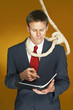 Photo: Businessman reading a document with a rope hanging around his neck. Businessman reading a document with a rope hanging around his neck.