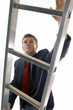 Photo: Man in business suit climbing up a ladder. Man in business suit climbing up a ladder.