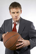 Man in business suit holding a basketball. 