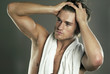 Shirtless man applying gel on his hair. 