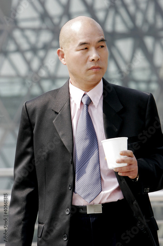 Foto: Bald man in business suit holding a cup. Bald man in business suit holding a cup.