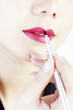 Woman applying colour on her lips.