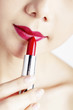 Woman applying lipstick on her lips.