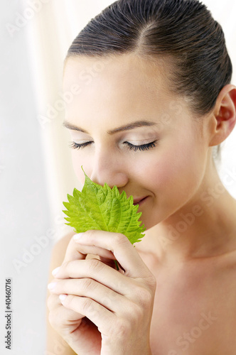 Photo: Woman smelling a green leaf. Woman smelling a green leaf.