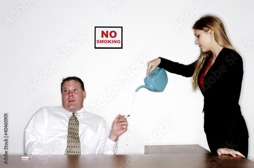 Photo: Businesswoman watering the cigarette from an ignorant businessman. Businesswoman watering the cigarette from an ignorant businessman.