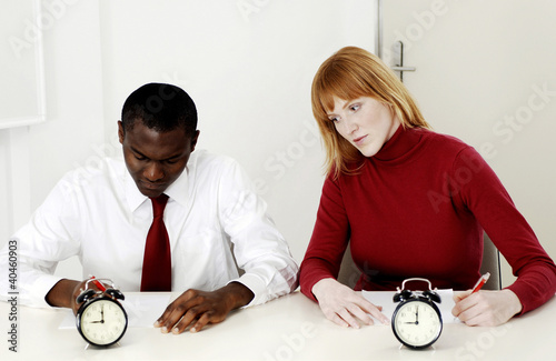 Photo: Businesswoman copying her colleague's work during a test. Businesswoman copying her colleague's work during a test.