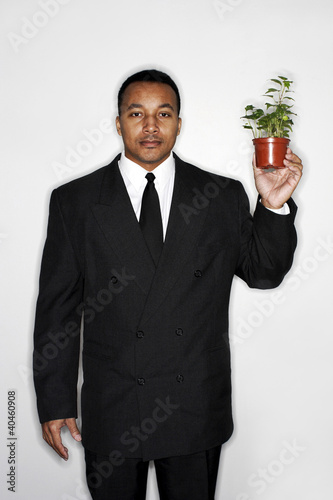 Photo: Businessman holding a pot of plants. Businessman holding a pot of plants.