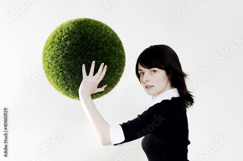 Foto: Businesswoman holding a grass ball. Businesswoman holding a grass ball.
