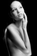 Topless woman touching her face.