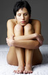 Naked woman sitting in a fetus position.
