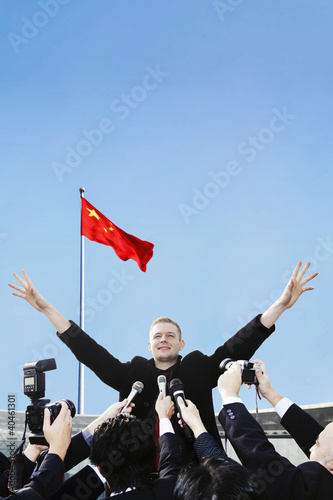 Photo: Businessman handling a group of reporters. Businessman handling a group of reporters.