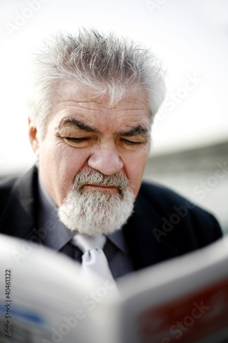 Photo: Senior businessman reading newspaper. Senior businessman reading newspaper.