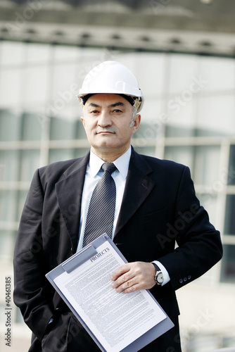 Photo: Senior businessman wearing a safety helmet. Senior businessman wearing a safety helmet.