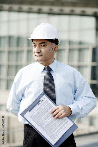 Photo: Senior businessman wearing a safety helmet. Senior businessman wearing a safety helmet.