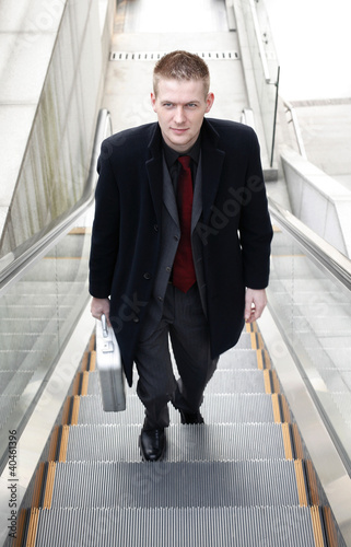 Photo: Businessman standing on an escalator. Businessman standing on an escalator.