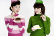 Women with party hats enjoying cakes.