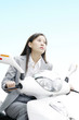 Businesswoman riding on a scooter.