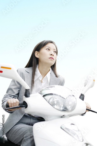Photo: Businesswoman riding on a scooter. Businesswoman riding on a scooter.