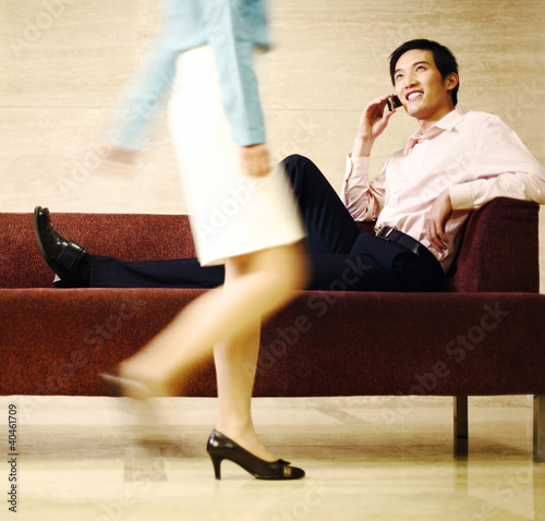 Photo: Businessman checking out a woman while talking on the handphone. Businessman checking out a woman while talking on the handphone.