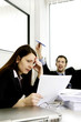 Businessman playing with paper plane while his colleague is busy working.