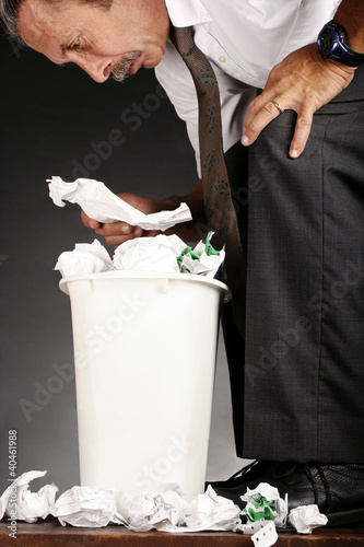 Photo: Businessman ransacking a dustbin. Businessman ransacking a dustbin.