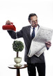 Businessman reading newspaper while watering the plants.
