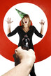 Hand aiming a pistol at a businesswoman with party hat.