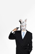Businessman with rabbit mask pointing a pistol at himself.