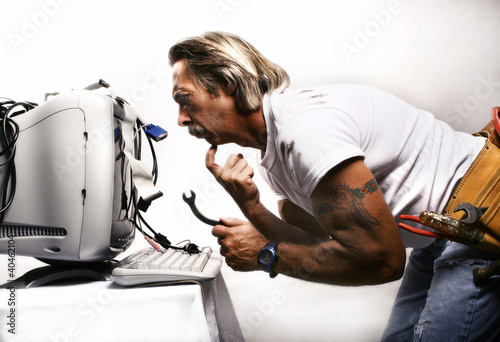 Photo: Businessman trying to fix his computer. Businessman trying to fix his computer.