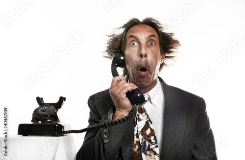 Photo: Businessman receiving a shocking phone call. Businessman receiving a shocking phone call.