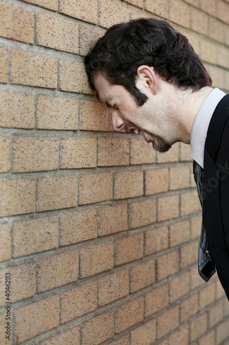 Photo: Businessman banging his head against the wall. Businessman banging his head against the wall.