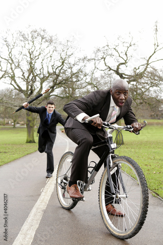 Foto: Businessman trying to beat another businessman with an umbrella. Businessman trying to beat another businessman with an umbrella.