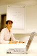 Foto: Businesswoman writing on the background with the focus on a laptop. Businesswoman writing on the background with the focus on a laptop.