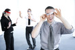 Businessman cheating during a blindfolding game.