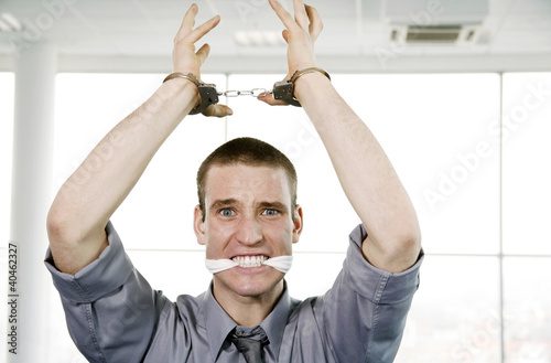 Photo: Businessman with his hands being cuffed and his mouth being stuffed with cloth. Businessman with his hands being cuffed and his mouth being stuffed with cloth.