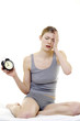 Drowsy woman holding an alarm clock.