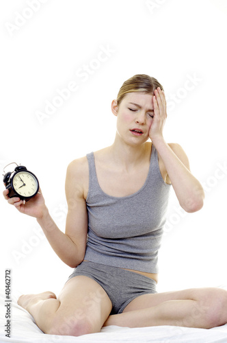Photo: Drowsy woman holding an alarm clock. Drowsy woman holding an alarm clock.